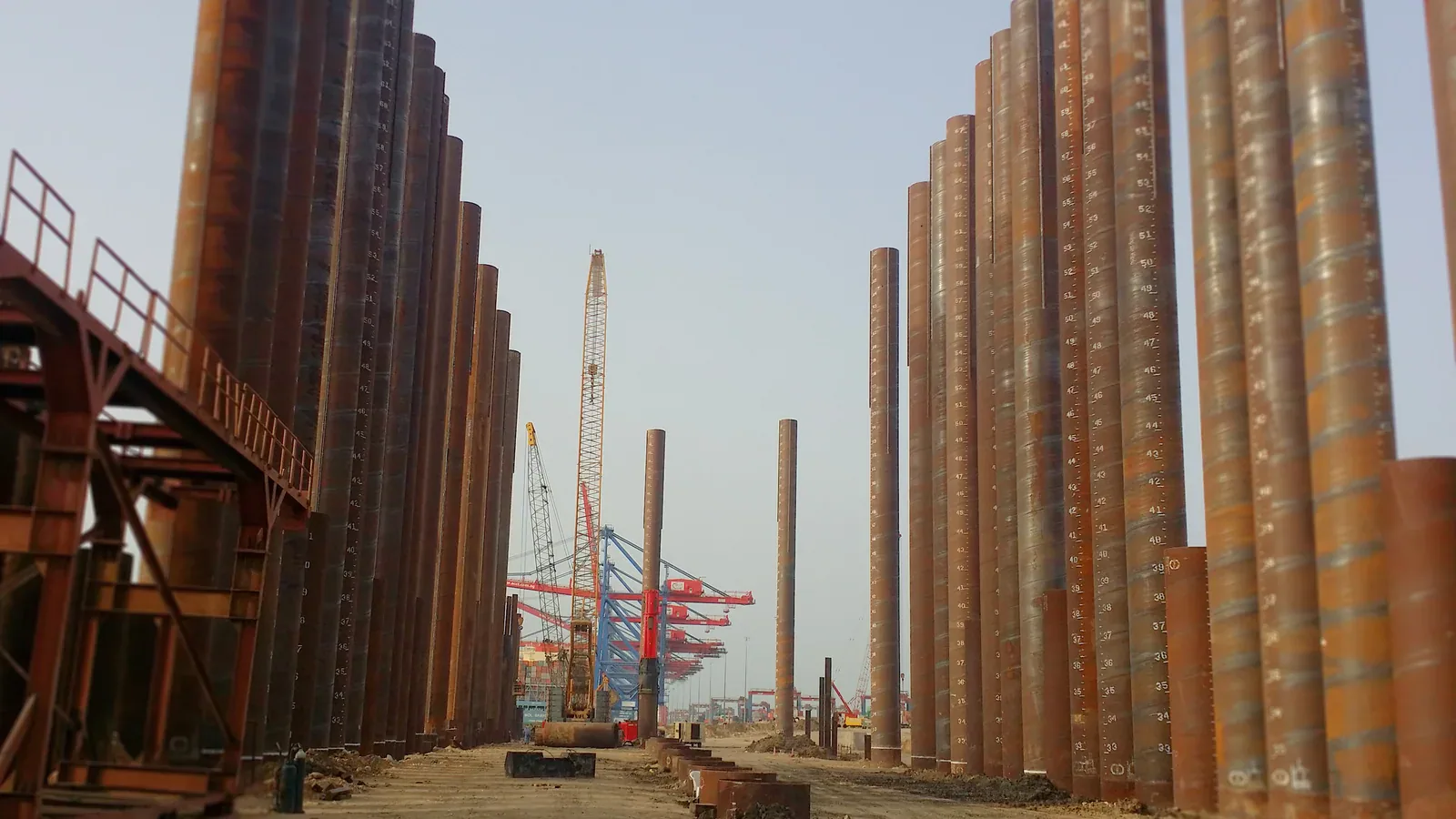 BRUCE hydraulic impact pile hammer among steel pipe piles at a waterfront construction site