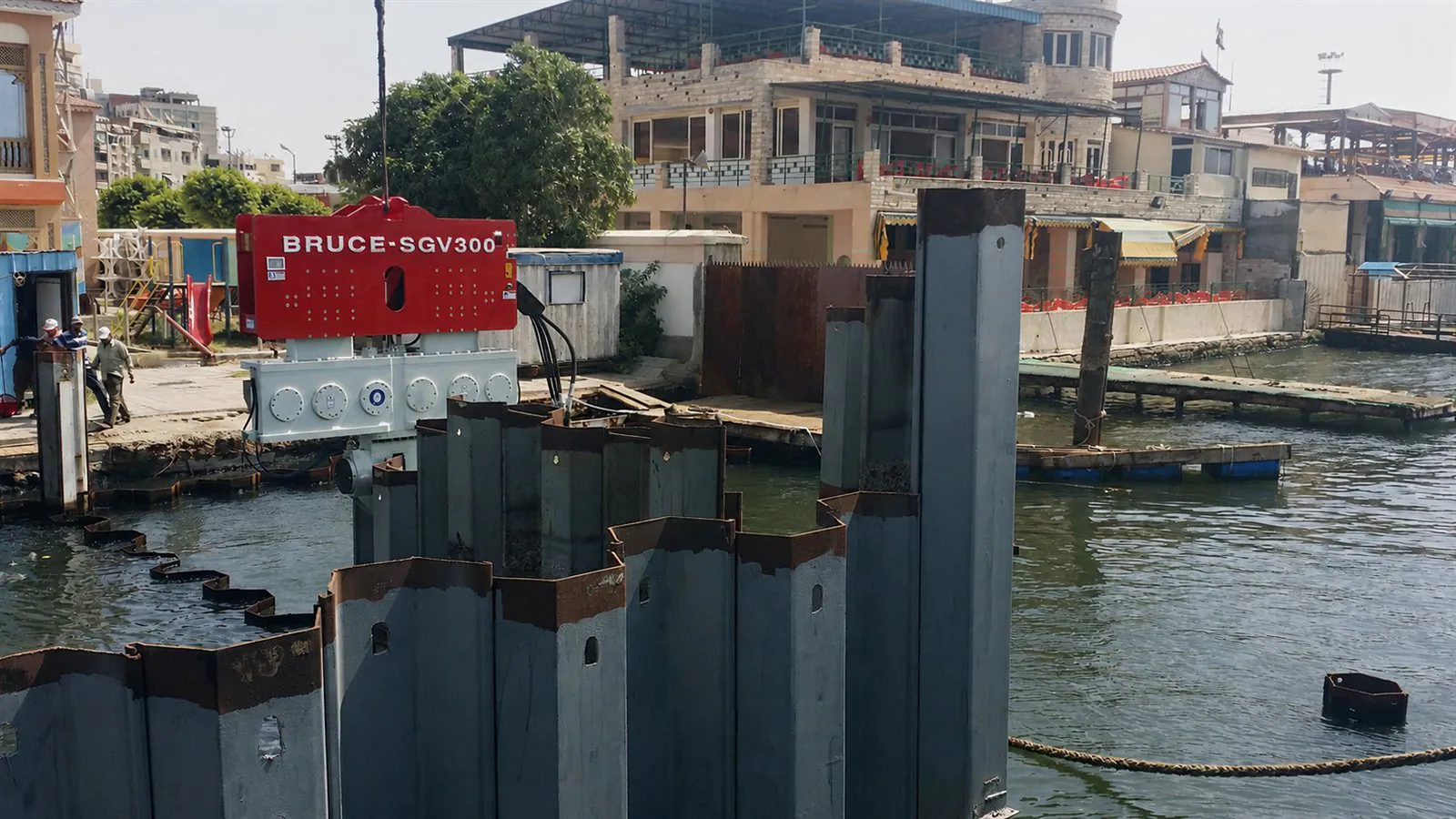 BRUCE SGV300 vibro hammer beside steel sheet piles at a waterfront site