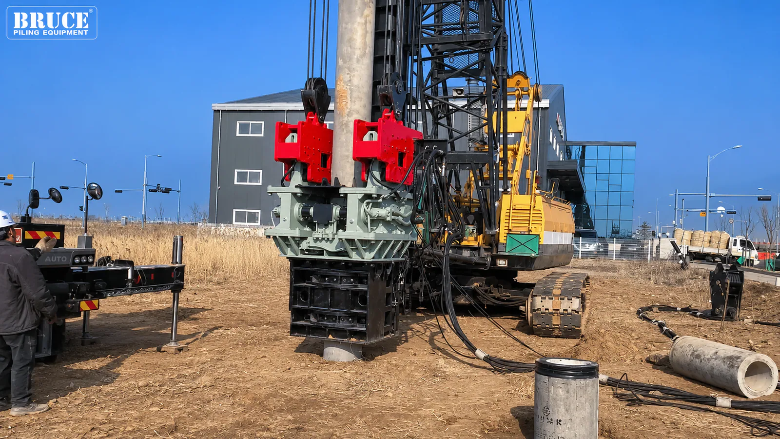 BRUCE vibratory hammer positioned around a cylindrical pile, with crane lines and hydraulic hoses